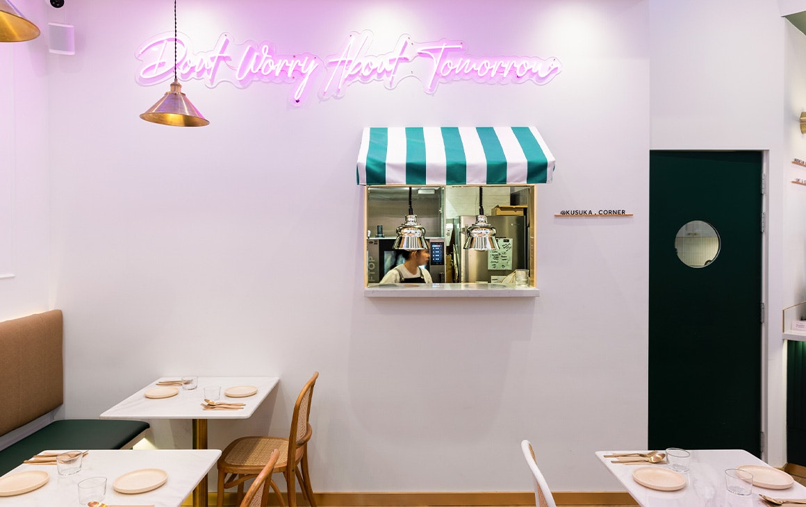 the dining area of kusuka corner with a neon sign and window into the kitchen